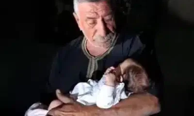 The grandfather of baby Lana Shahada, whose home was attacked by Israeli settlers, holds her and looks down at her