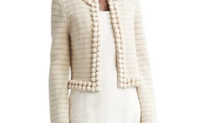 A woman wearing an ivory trimmed cardigan over an over an off-white dress