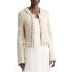 A woman wearing an ivory trimmed cardigan over an over an off-white dress