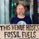 QEII fossil fuel protest Protester holds sign saying This Venue Hosts Fossil Fuels