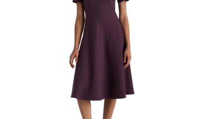 A woman wearing a dark purple midi dress and black strappy heels