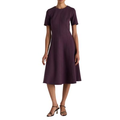 A woman wearing a dark purple midi dress and black strappy heels