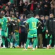 Senegal players standing on the pitch at AFCON final, some wearing only their kits and others with puffer jackets on
