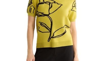 A woman wearing black pants and a yellow-green top with a black floral outline