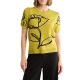 A woman wearing black pants and a yellow-green top with a black floral outline