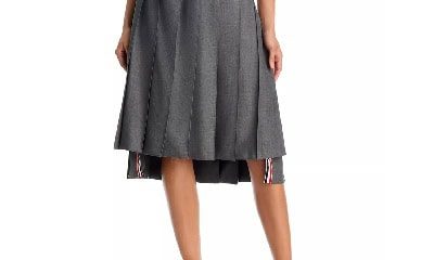 A woman wearing a white top (upper half of body cropped out), black heels, and gray skirt with partial striped trim