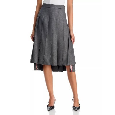 A woman wearing a white top (upper half of body cropped out), black heels, and gray skirt with partial striped trim