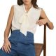 A woman sitting on a chair, wearing an ivory tie-neck blouse and high-waisted blue jeans