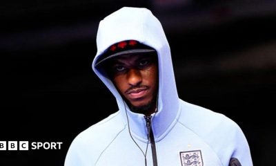 Marcus Rashford wearing a white England zip-up top, hood pulled up over his head