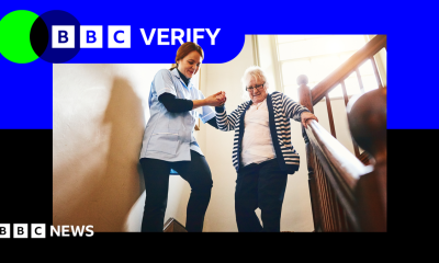 A care worker helps a woman down a flight of stairs