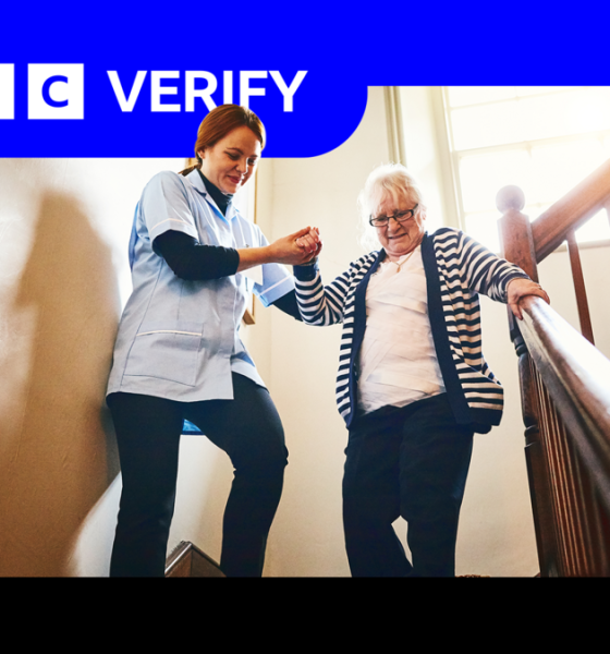 A care worker helps a woman down a flight of stairs