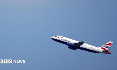 A British Airways Airbus A320 flies up through a blue sky.