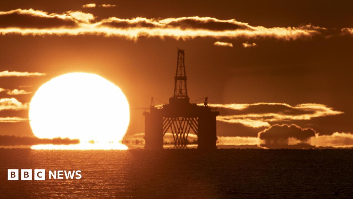 The sun on he horizon behind an oil and gas platform in the North Sea. The sea is calm and the whole scene is a vivid orange colour.