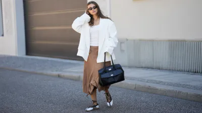 BERLIN, GERMANY - MAY 27: Lisa Mottl is seen wearing an off-white double-breasted oversized blazer with sharp wide peak lapels, padded shoulders, long sleeves, two parallel rows of matching fabric-covered buttons and classic horizontal flap pockets from Bazhane; a white fitted top from Zara; camel brown cargo-inspired cropped capri length trousers with belt loops, angled flap pockets, wide fluid legs and adjustable drawstring toggle hems creating a gathered balloon-like silhouette from Zara; off-white leather