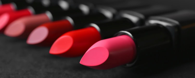 tubes of lipstick laying on a dark surface