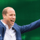 A designed image of Prince William cheering with his arms up over a green background.