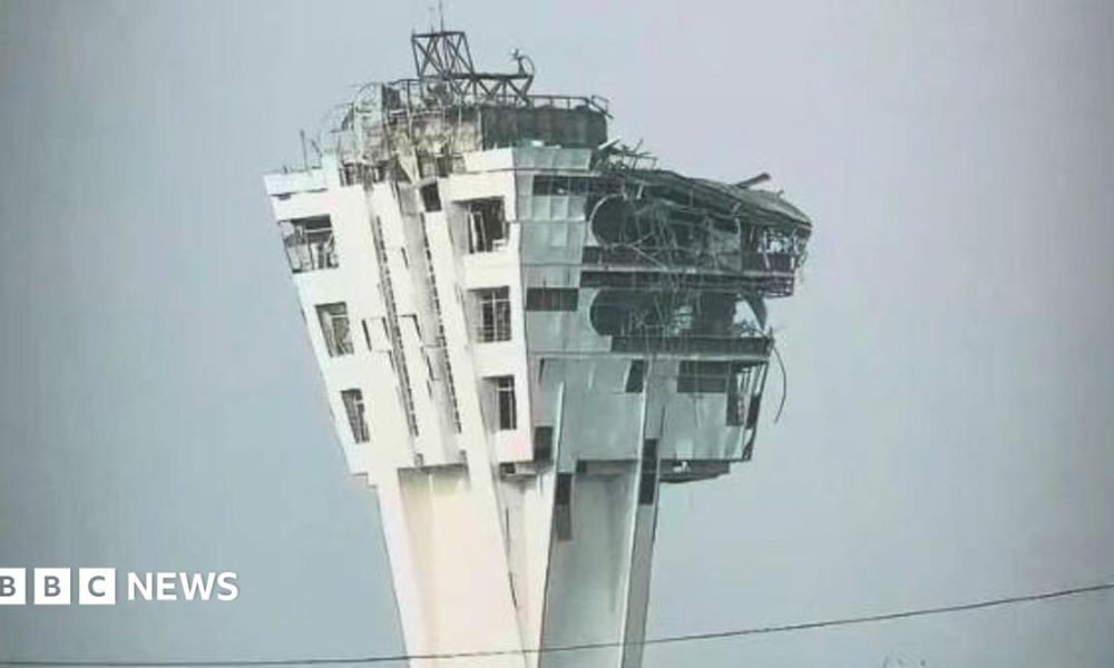A large control tower is shown with windows blown out and the exterior crumbling