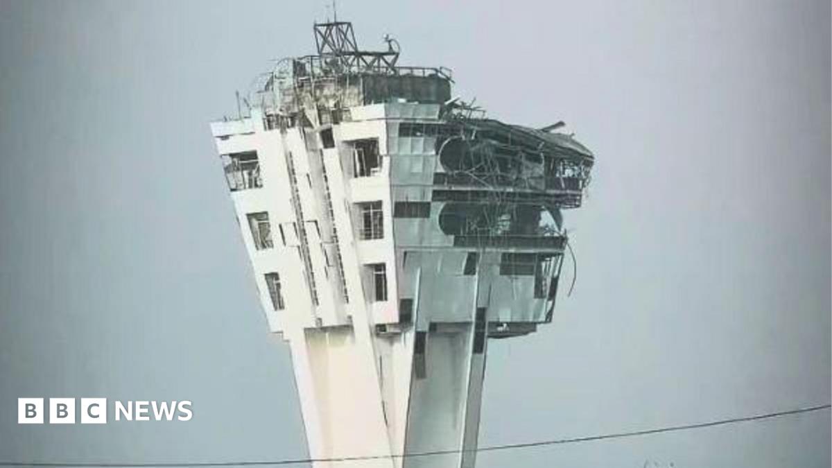 A large control tower is shown with windows blown out and the exterior crumbling