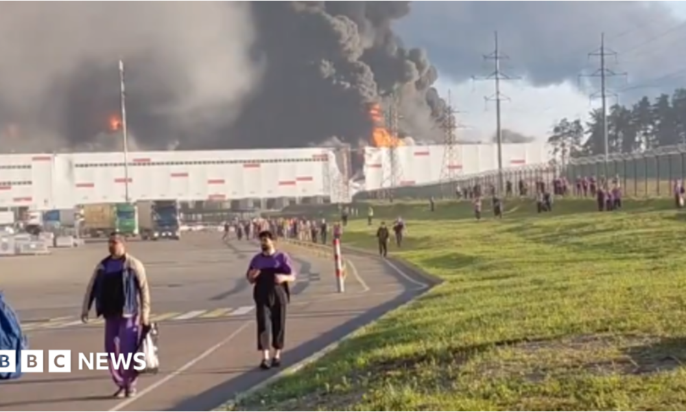 people walk away from a burning warehouse