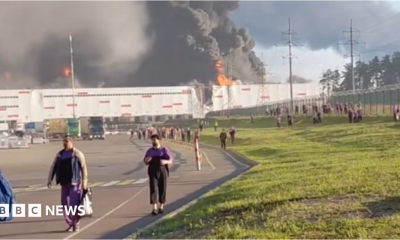 people walk away from a burning warehouse