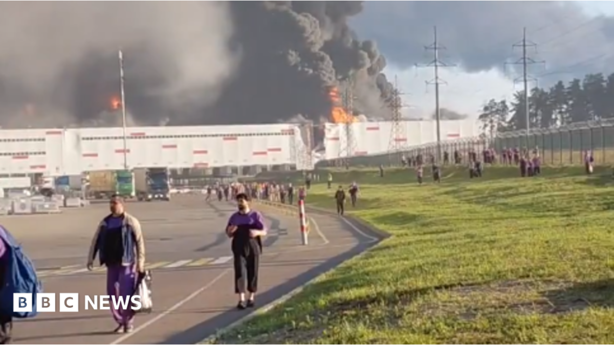 people walk away from a burning warehouse