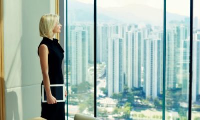 blonde woman stares out window in a large private office