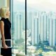 blonde woman stares out window in a large private office