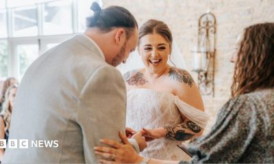 A bride and grown walk down the aisle in a brick barn