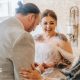 A bride and grown walk down the aisle in a brick barn