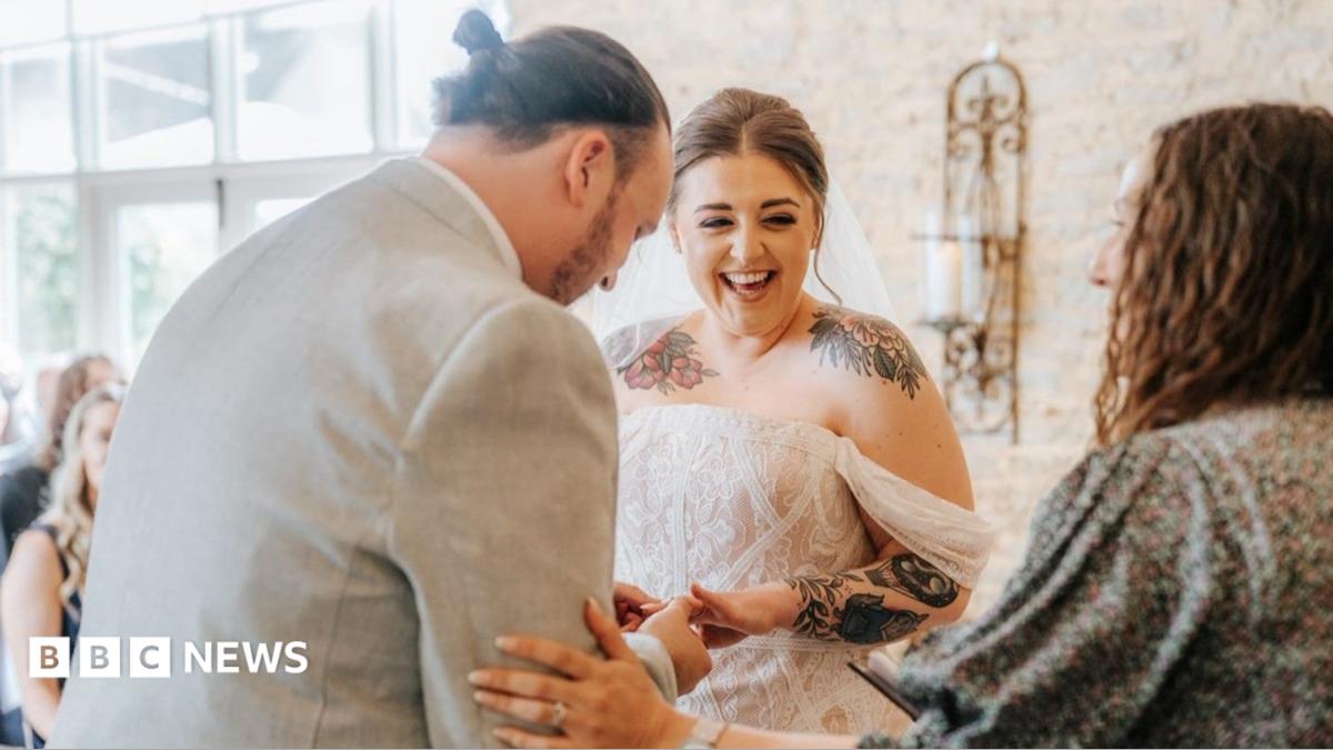 A bride and grown walk down the aisle in a brick barn
