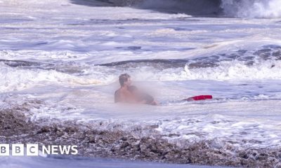 A life guard holds a child in the ocean.