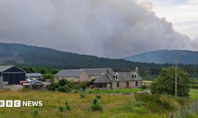 smoke over hills beyond farm buildings