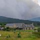 smoke over hills beyond farm buildings