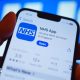 A hand holds a smartphone displaying the NHS app after it has been downloaded.