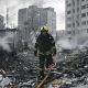Sarah Rainsford in a brown shirt with short sleeves in front of rubble in Kyiv