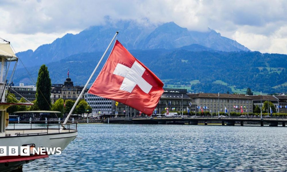 A view of a Swiss flag on a boat on lake Lucerne and Lucerne city in central Switzerland