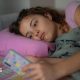 A stock image shows a young woman lying down with a glum expression as she scrolls on her smartphone