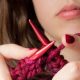 woman knits with red yarn
