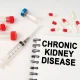 On the table are pills, injections, a syringe and a notepad with the inscription - chronic kidney disease
