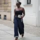 BERLIN, GERMANY - JULY 4: Lois Opoku is seen wearing a black ribbed strapless top with a sweetheart neckline from Uniqlo; dark blue high waist wide leg denim jeans with turned up cuffs from Levi’s; a slim leopard print belt from H&M Studio; leopard print pointed toe Mary Jane pumps from H&M Studio; a Chanel Mini CC bicolor chevron stitched lambskin flap shoulder bag with a gold tone chain strap; a gold collar necklace from Alexis Bittar and a gold pendant necklace from Bruna the Label; gold hoop earrings from ASOS; gold cuff bracelets and a gold chain bracelet from Petite Villa Mauresque; rings from Pandora and Maria Black; oval tortoiseshell frame sunglasses with dark tinted lenses from Corlin during the Berlin Fashion Week Spring/Summer 2026 on July 4, 2026 in Berlin, Germany. (Photo by Moritz Scholz/Getty Images)