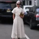 NEW YORK, NEW YORK - FEBRUARY 13: Grece Ghanem seen wearing a long white blouse dress, a golden Carolina Herrera bag, Gucci pink heels and dark shades before the Carolina Herrera show on February 13, 2023 in New York City. (Photo by Jeremy Moeller/Getty Images)