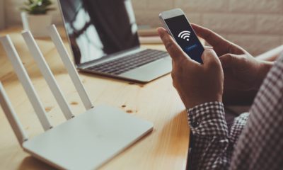 Closeup,Of,A,Wifi,Router,And,A,Man,Using,Smartphone