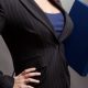 a professional woman holds a folder; she is wearing a blazer and does in fact look busty