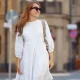 A young woman in a white dress walks through the streets of the city. People, fashion, lifestyle, travel and vacations concept