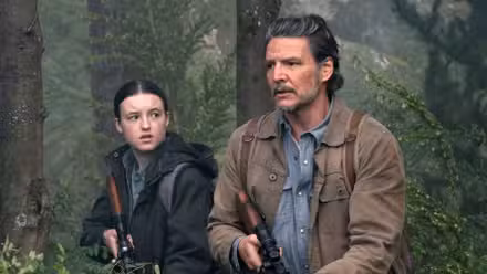 Bella Ramsey as Ellie with Pedro Pascal as Joel in the woods holding rifles in The Last of Us Season 2