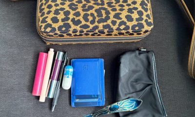 image of what's in Kat's bag on July 1, 2026: black pouch, blue wallet, blue hair clip, purple mirror with elastic wrapped around it, 2 lip glosses, concealer, and a (very old) pill case. The purse itself is leopard from Rothy's.