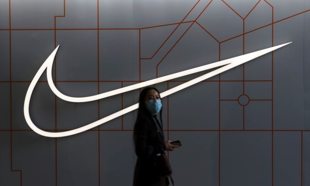 Woman walks past a Nike Inc store at a shopping complex in Beijing