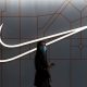 Woman walks past a Nike Inc store at a shopping complex in Beijing
