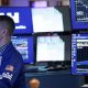 A stock market trader monitors screens on the stock market