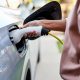 A woman plugs a charging cable into a grey electric car.